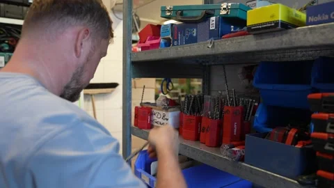 Warehouse worker selecting drill bits and small tool accessories from organized Видео 331305137