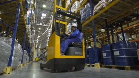 Warehouse worker on stacker loading cargo on shelf Stock Footage 76002006