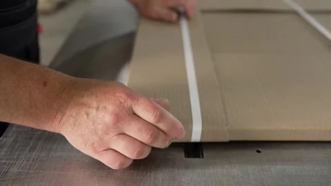 Warehouse worker strapping cardboard package using machine Stock Footage 327124341