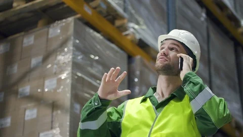 Warehouse worker talking on the phone. architect in logistics shelves of factory Stock Footage 124452033