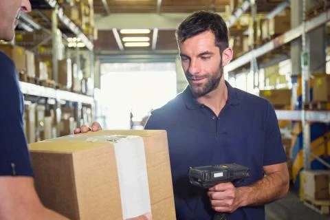 Warehouse worker using barcode scanner on cardboard box in distribution Stock Photos