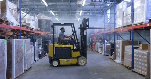 Warehouse worker using a forklift to lift a shipment pellet in warehouse Stock Footage 116368836