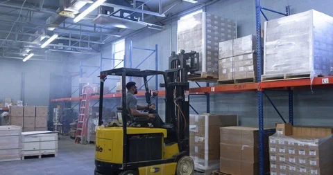 Warehouse worker using a forklift to place shipment pellet in warehouse Stock Footage 116365683