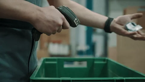 Warehouse worker using a handheld barcode scanner to process items in a green Stock Footage 335861686