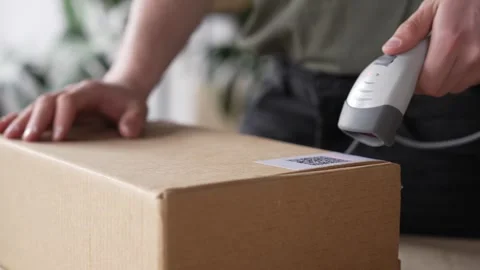 Warehouse worker using a QR code reader, scanning parcels into the system 스톡 동영상 272391828