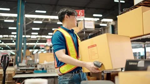 Warehouse worker using a QR code reader, scanning parcels into the system Foto stock