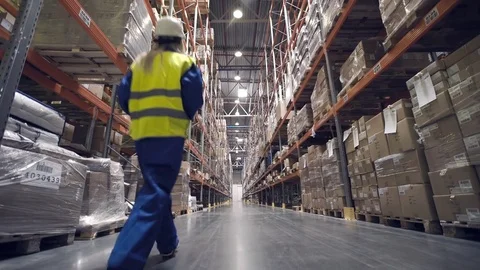 Warehouse worker walks through rows of warehouse Stock Footage 76044987