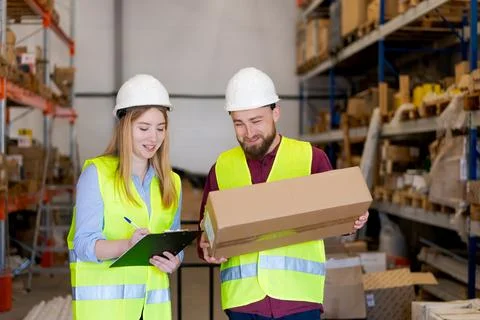 Warehouse workers checking package delivery with inventory list Stock Photos