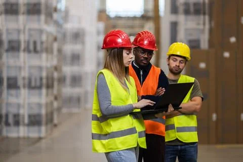 Warehouse workers collaborating on a project using a laptop computer Stock Photos