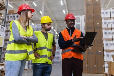 Warehouse workers discussing project details while reviewing data on a laptop Stock Photos