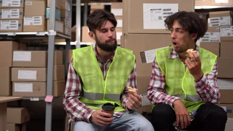 Warehouse workers having lunch at workplace, communicating and eating sandwiches Stock Footage 259940777