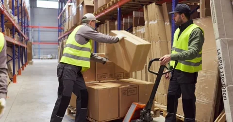Warehouse workers loading boxes onto pallet with manual trolley for delivery Stock Footage 327675580