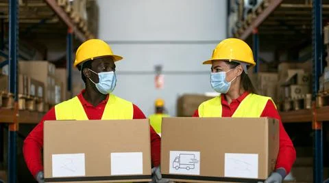 Warehouse workers loading delivery boxes while wearing face mask Stockfoto's