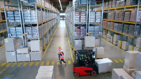 Warehouse workers navigate aisles between high shelves and large crates. 库存影片 307996706