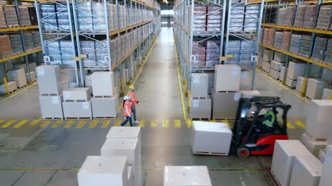 Warehouse workers navigate aisles with safety vests and hard hats. 動画素材 307997358