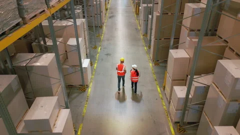 Warehouse workers navigate aisles in a storage facility. Stock-Footage 308002363
