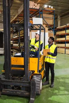 Warehouse workers operating forklift handling wood materials Stock Photos