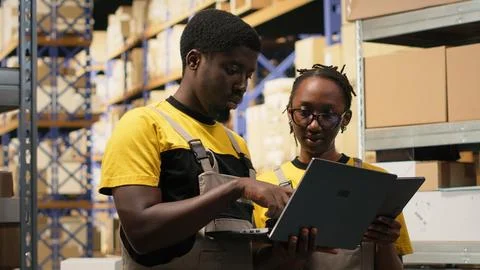 Warehouse workers overseeing parcels tracking info on gadgets Stock Photos
