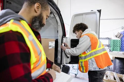 Warehouse workers photographing bar code on box in van Stock Photos