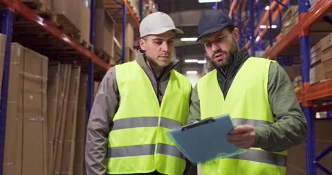 Warehouse workers reviewing inventory checklist clipboard for delivery logistics Stock Footage 335475789