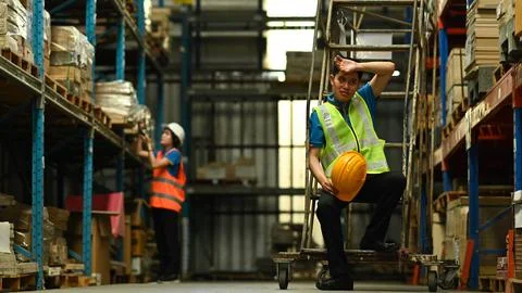Warehouse workers in safety uniform working in warehouse full of tall shelves Stockfoto's