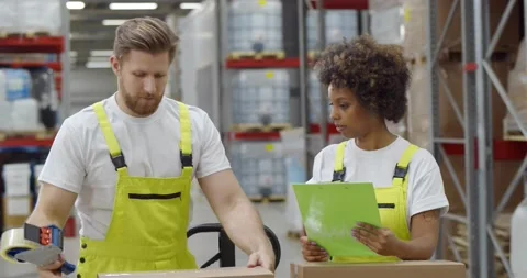 Warehouse workers sealing cardboard boxes for shipping in large warehouse Stock Footage 151404613