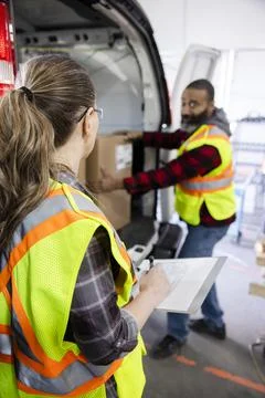 Warehouse workers unloading boxes from van at loading dock Stock Photos