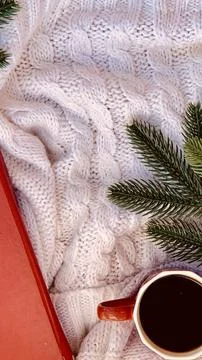 Warm and inviting winter decor featuring a white knitted blanket, a red book, a Foto stock