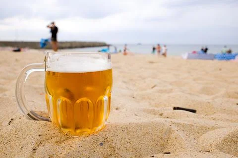 On a warm August day, a cold beer mug on Kolobrzeg beach captures the calm .. Stock Photos