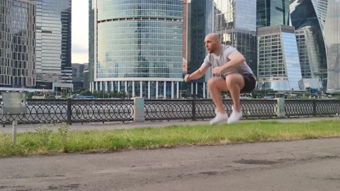 Warm-up of a bald, young man. Jumping with raising the knee to the chest. Stock Footage 201303378