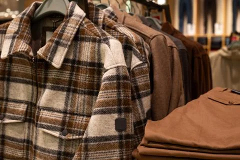 Warm beige jacket with checkerboard pattern on hanger in clothing store. Conc Stock Photos