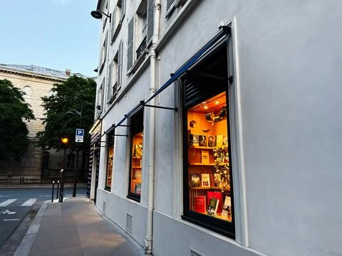 Warm bookstore window display on a quiet Paris street at dusk, France, with.. Stock-Fotos