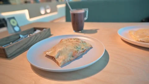 A warm breakfast dish is placed on a table, featuring an omelet with a hot drink Stock Footage 339005032