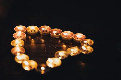 Warm candlelight forms a heart shape on dark wood Foto stock