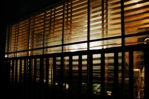 Warm Cinematic Desk Setup Viewed Through Window Blinds at Night Stock Photos
