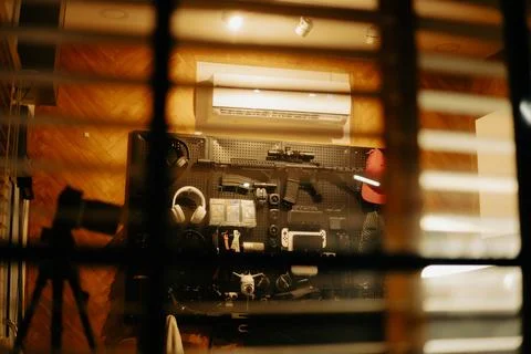 Warm Cinematic Desk Setup Viewed Through Window Blinds at Night Stock Photos