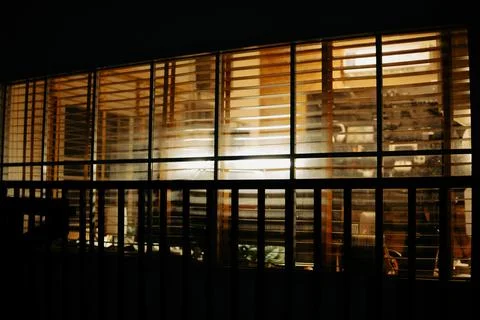 Warm Cinematic Desk Setup Viewed Through Window Blinds at Night Stock Photos