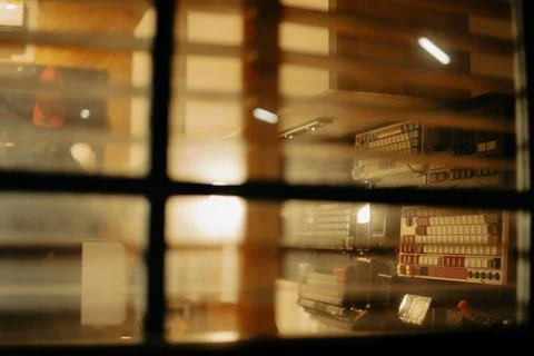 Warm Cinematic Desk Setup Viewed Through Window Blinds at Night Stock Photos