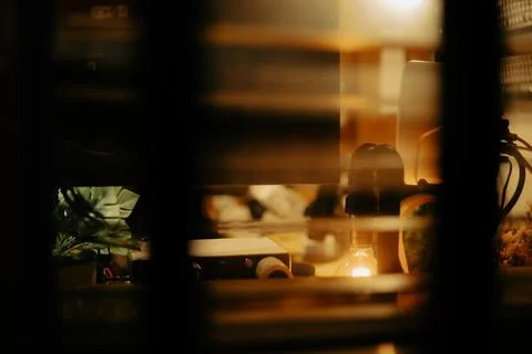 Warm Cinematic Desk Setup Viewed Through Window Blinds at Night Stock Photos