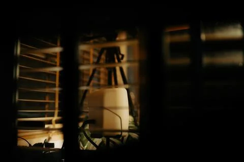 Warm Cinematic Desk Setup Viewed Through Window Blinds at Night Stock Photos