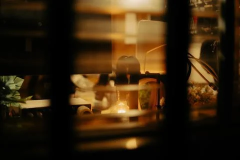 Warm Cinematic Desk Setup Viewed Through Window Blinds at Night Stock Photos
