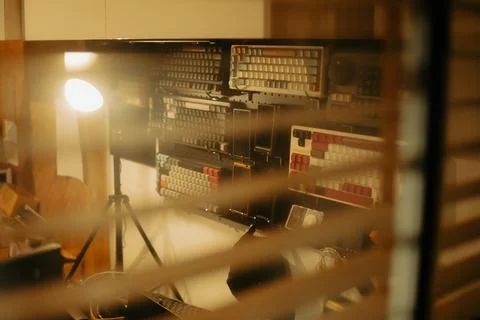 Warm Cinematic Desk Setup Viewed Through Window Blinds at Night Stock Photos