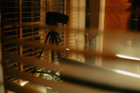 Warm Cinematic Desk Setup Viewed Through Window Blinds at Night Stock Photos