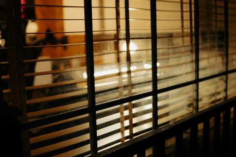 Warm Cinematic Desk Setup Viewed Through Window Blinds at Night Stock Photos