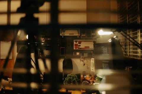 Warm Cinematic Desk Setup Viewed Through Window Blinds at Night Stock Photos