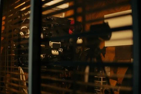 Warm Cinematic Desk Setup Viewed Through Window Blinds at Night Stock Photos