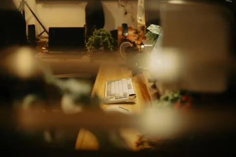 Warm Cinematic Desk Setup Viewed Through Window Blinds at Night Stock Photos