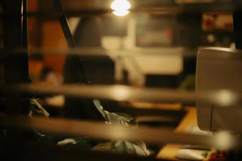 Warm Cinematic Desk Setup Viewed Through Window Blinds at Night Stock Photos