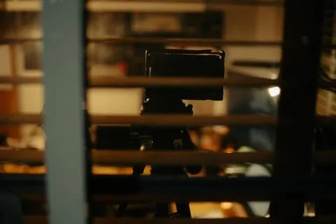 Warm Cinematic Desk Setup Viewed Through Window Blinds at Night Stock Photos
