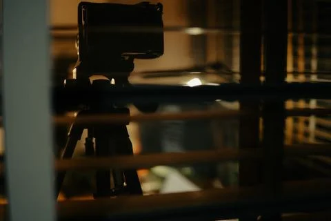 Warm Cinematic Desk Setup Viewed Through Window Blinds at Night Stock Photos